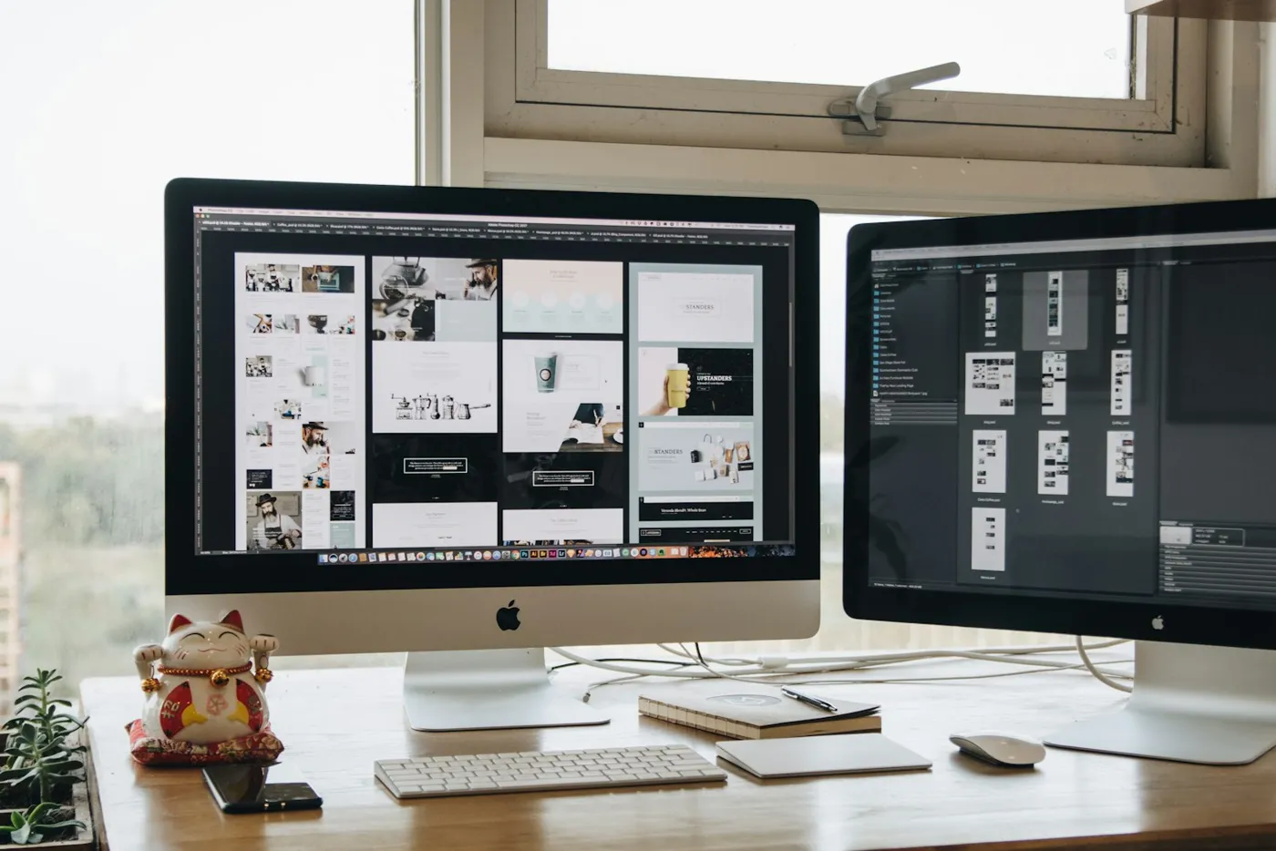 Două monitoare cu machete de site-uri pe un birou de web design